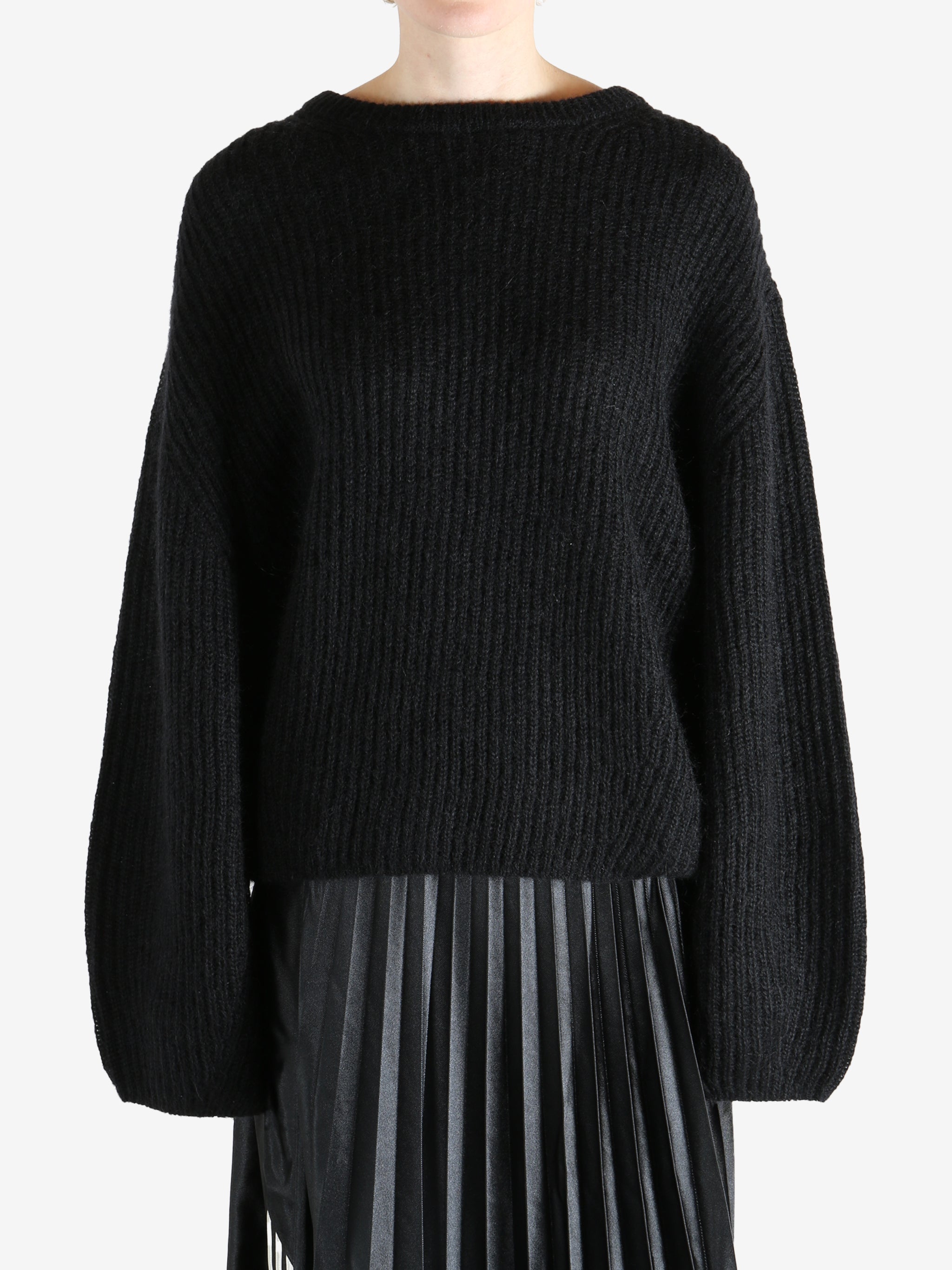 Black knitwear worn by a person, showing the knitwear fit