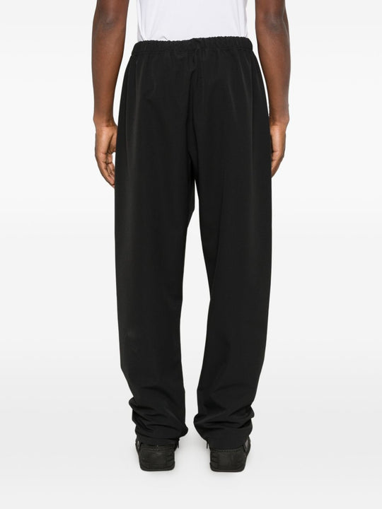 Black pants worn by a person, showing the pants' fit