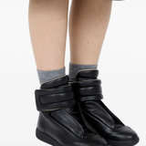 Black sneakers worn by a person, showing the black sneakers' fit