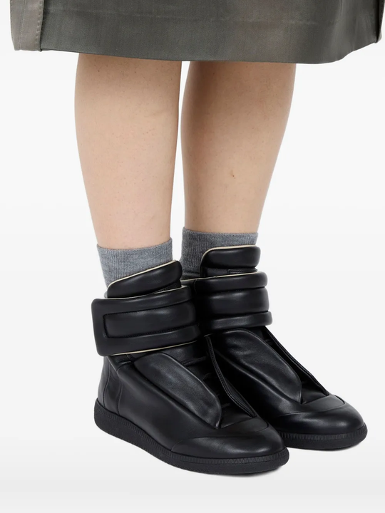 Black sneakers worn by a person, showing the black sneakers' fit
