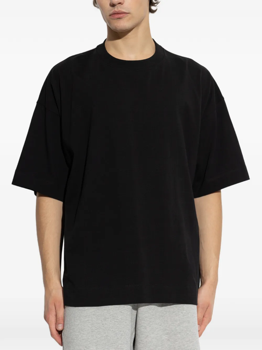 black t-shirts worn by a person, showing the t-shirts  fit