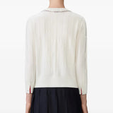 White knitwear worn by a person, showing the knitwear's fit