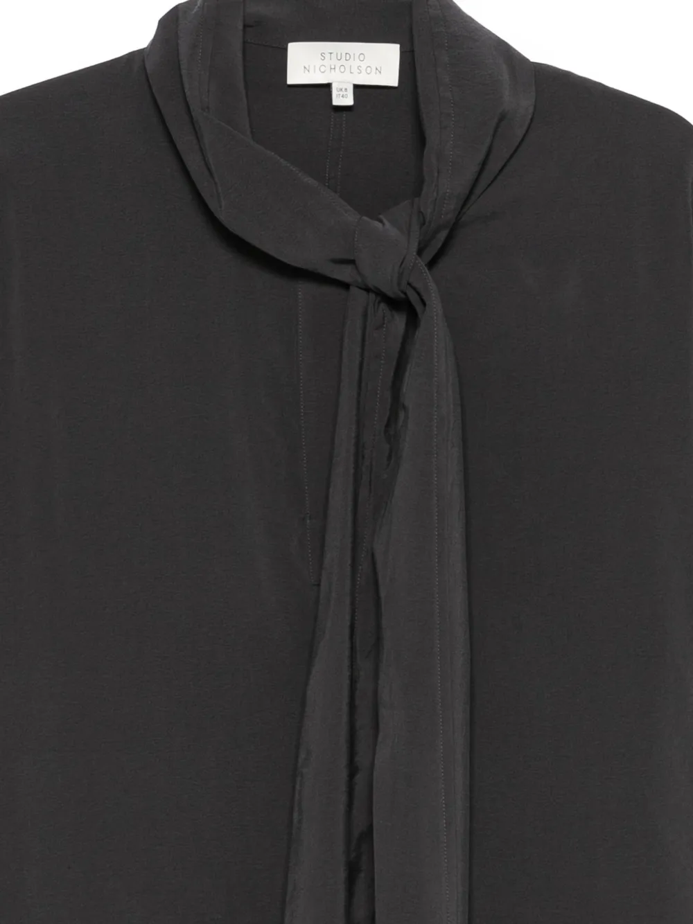 Close up of balck shirt, showing the detail of tie collar