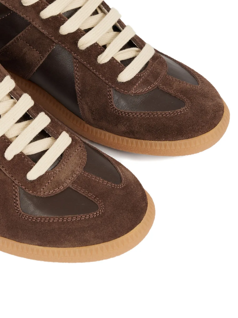 Close up of the brown sneakers, showing texture of the leather fabric