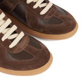 Close up of the brown sneakers, showing texture of the leather fabric