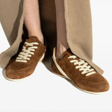 Brown sneakers worn by a person, showing the sneakers' fit