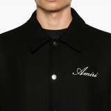 Black coat with 'Amiri' branding on a white background