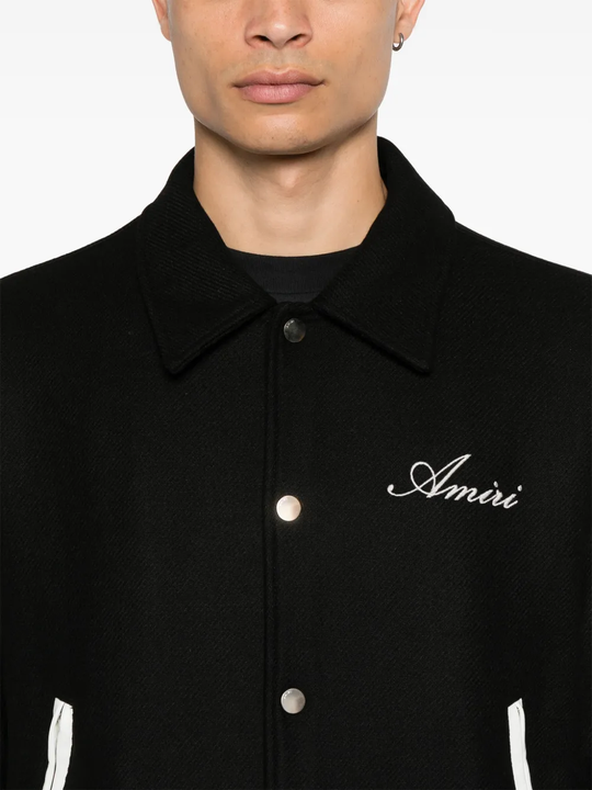Black coat with 'Amiri' branding on a white background