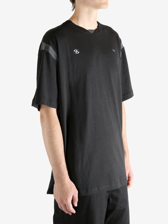 Black tee worn by a person, showing the tee"s fit