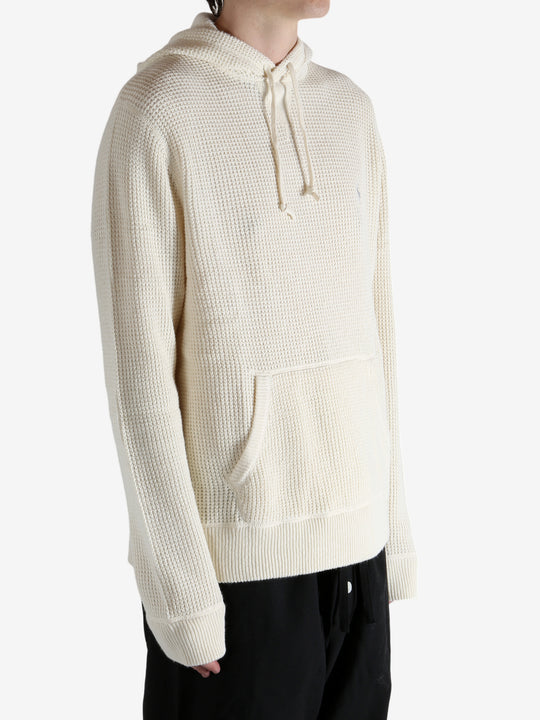 White knitwear worn by a person, showing the knitwear's fit