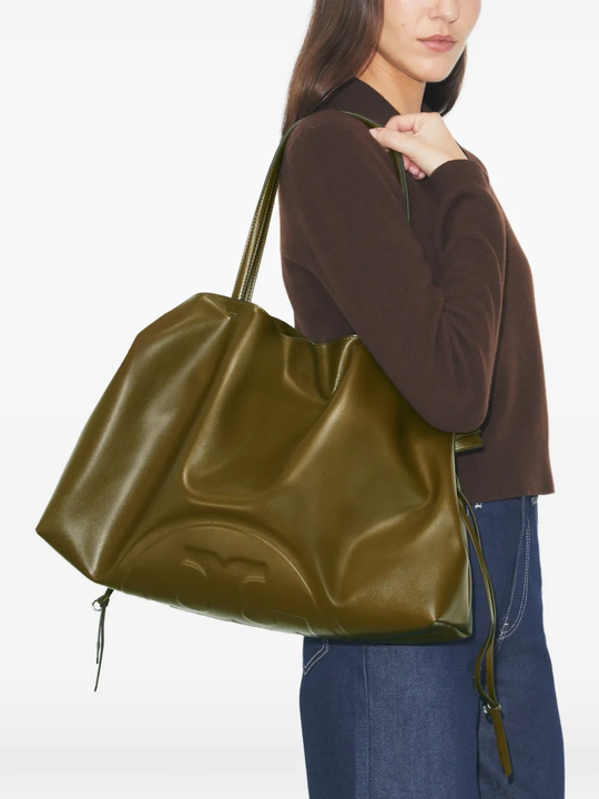Person holding a large green handbag against a white background