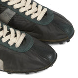 Close up of black sneakers, showing texture of the leather and rubber and polyester fabric
