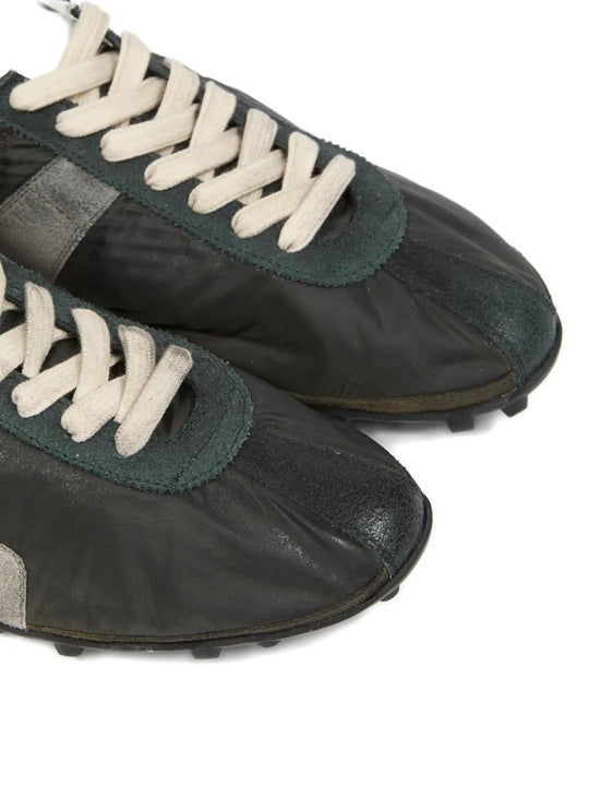 Close up of black sneakers, showing texture of the leather and rubber and polyester fabric