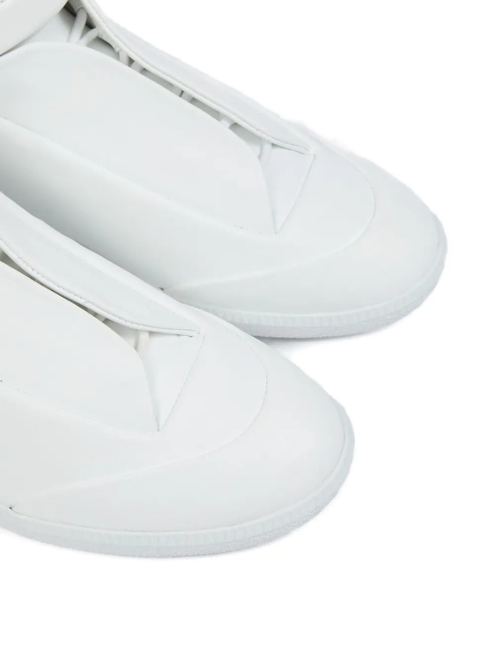 Close up of white sneakers, showing texture of the calf leather and rubber fabric