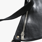 Close-up of a black leather bag with a zipper and strap details on a white background