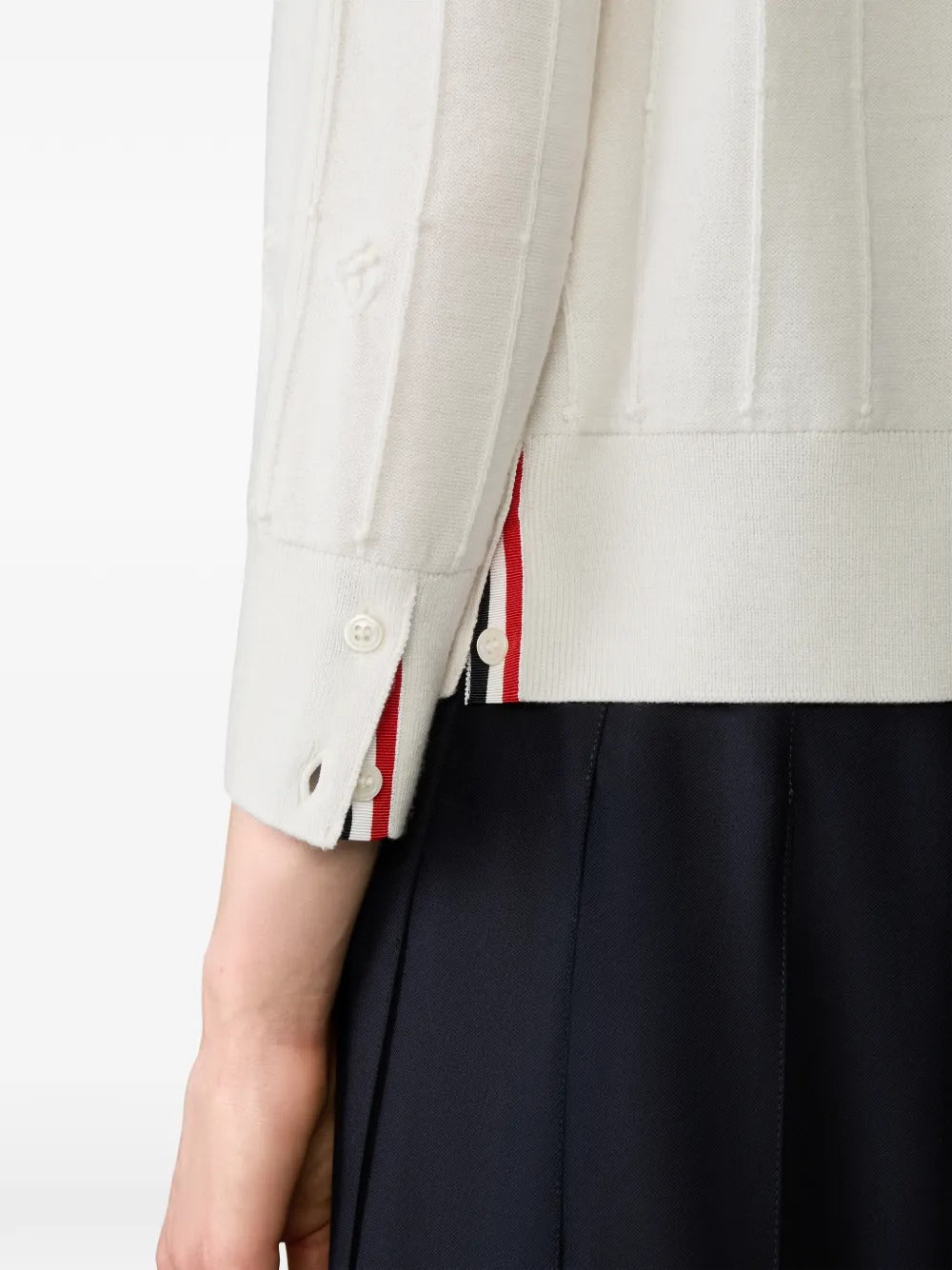 Close up of the white knitwear, showing texture of the wool fabric