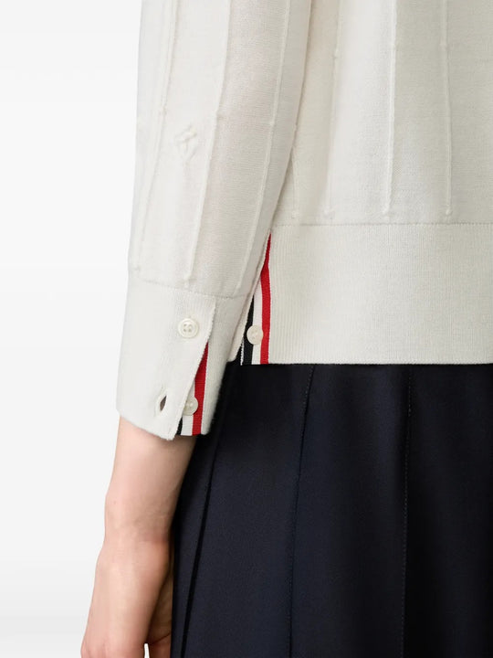 Close up of the white knitwear, showing texture of the wool fabric