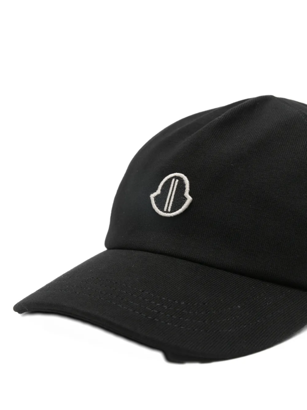 Close up of black cap, showing the logo detail and the texture of the cotton fabric