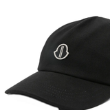 Close up of black cap, showing the logo detail and the texture of the cotton fabric