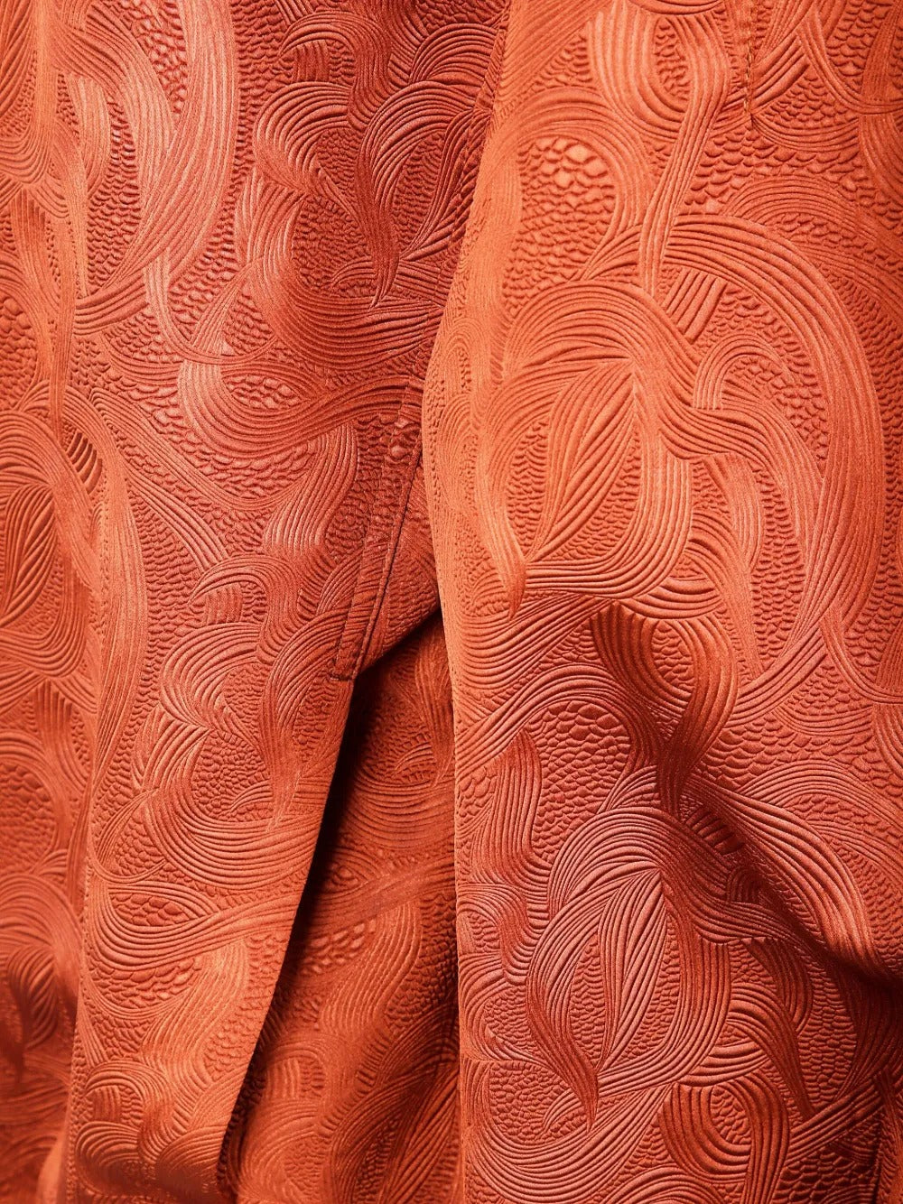 Close up of the orange jacket, showing texture of the polyester fabric