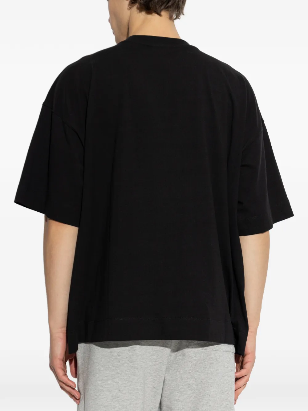 black t-shirts worn by a person, showing the t-shirts  fit