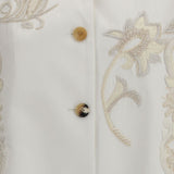 Close-up of a white garment with floral embroidery and buttons