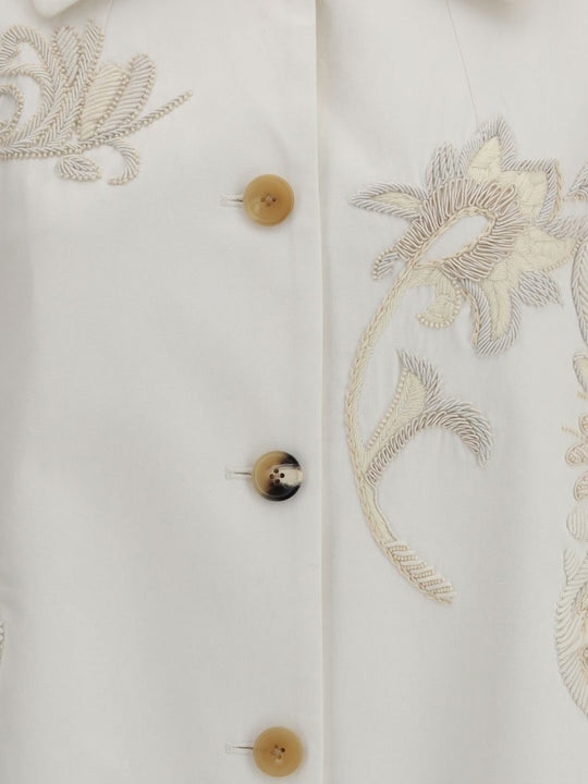 Close-up of a white garment with floral embroidery and buttons