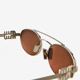 Close up of the brown sunglasses, showing texture of the metal fabric