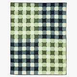 Woven checkered quilt with green, blue, and white squares on a white background