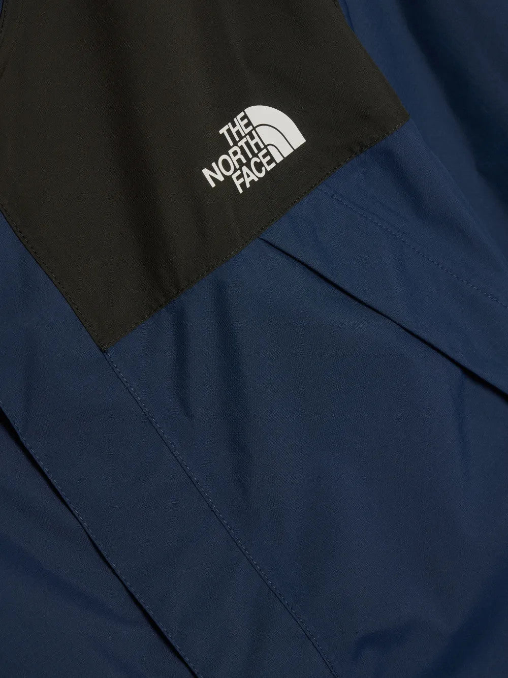 Close up of Navy jacket, showing texture of the 100% recycled nylon made fabric