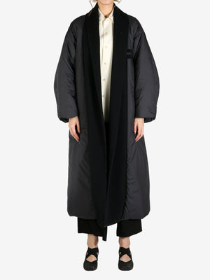 Black coat worn by a person, showing the coat fit