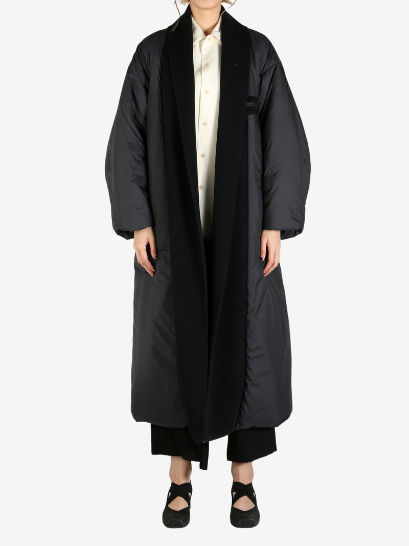 Black coat worn by a person, showing the coat fit