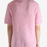 Pink knitwear worn by a person, showing the knitwear's fit