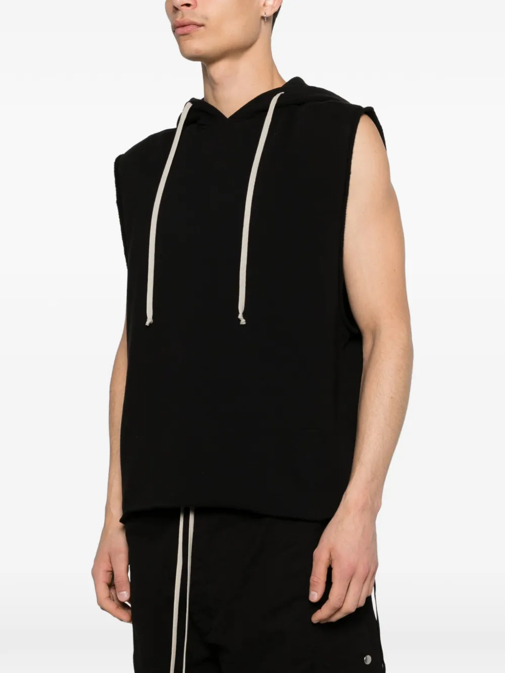 Black sleeveless hoodie worn by a person, showing the shirt's fit