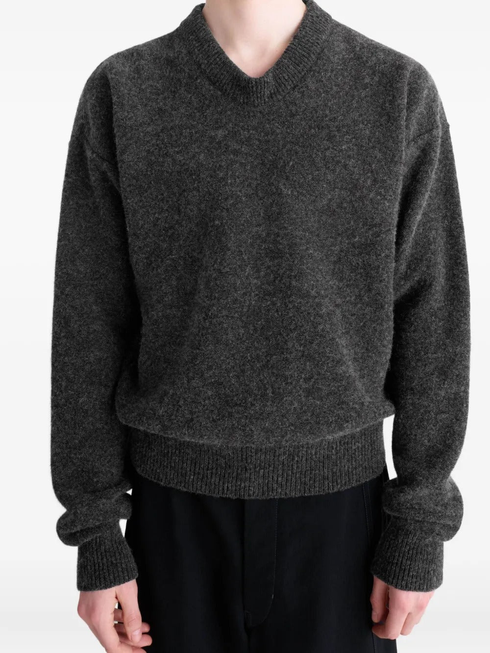 Black sweater worn by a person, showing the sweater's fit