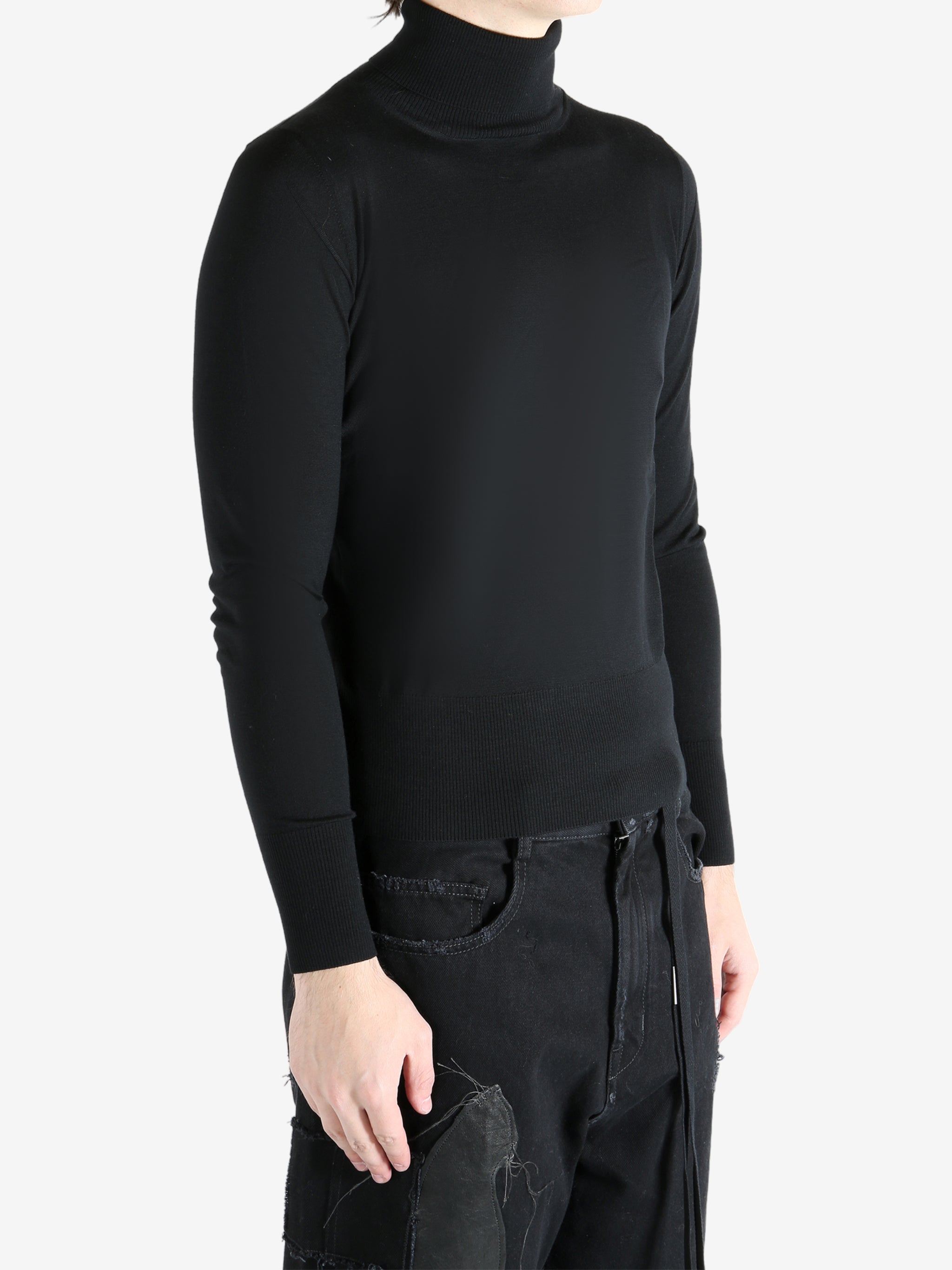 Black sweater worn by a person, showing the sweater's fit
