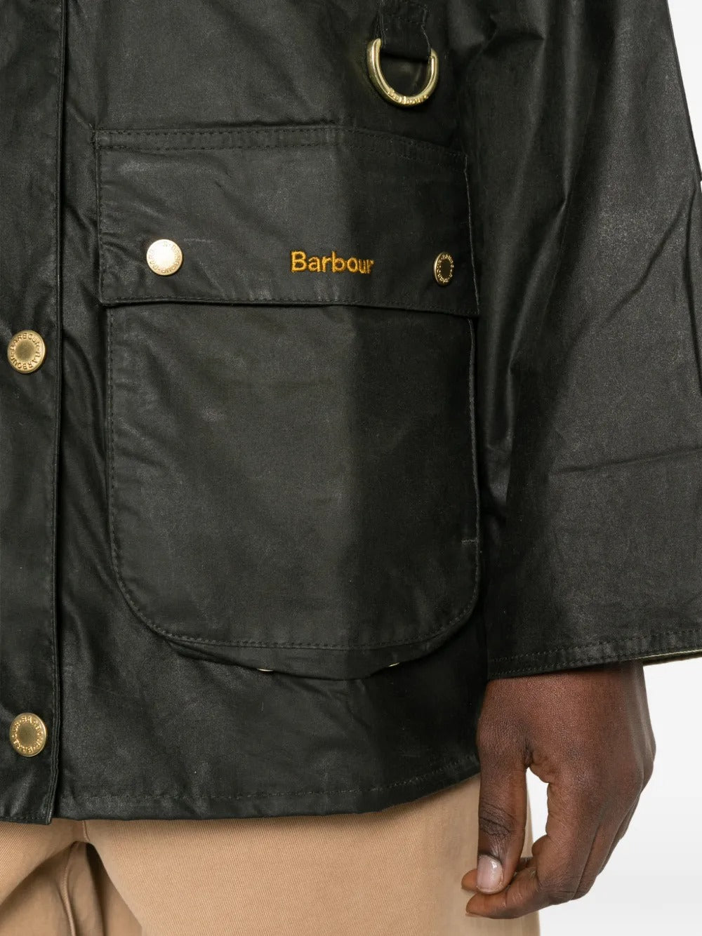 Close-up of a black jacket with gold buttons and 'Barbour' branding.