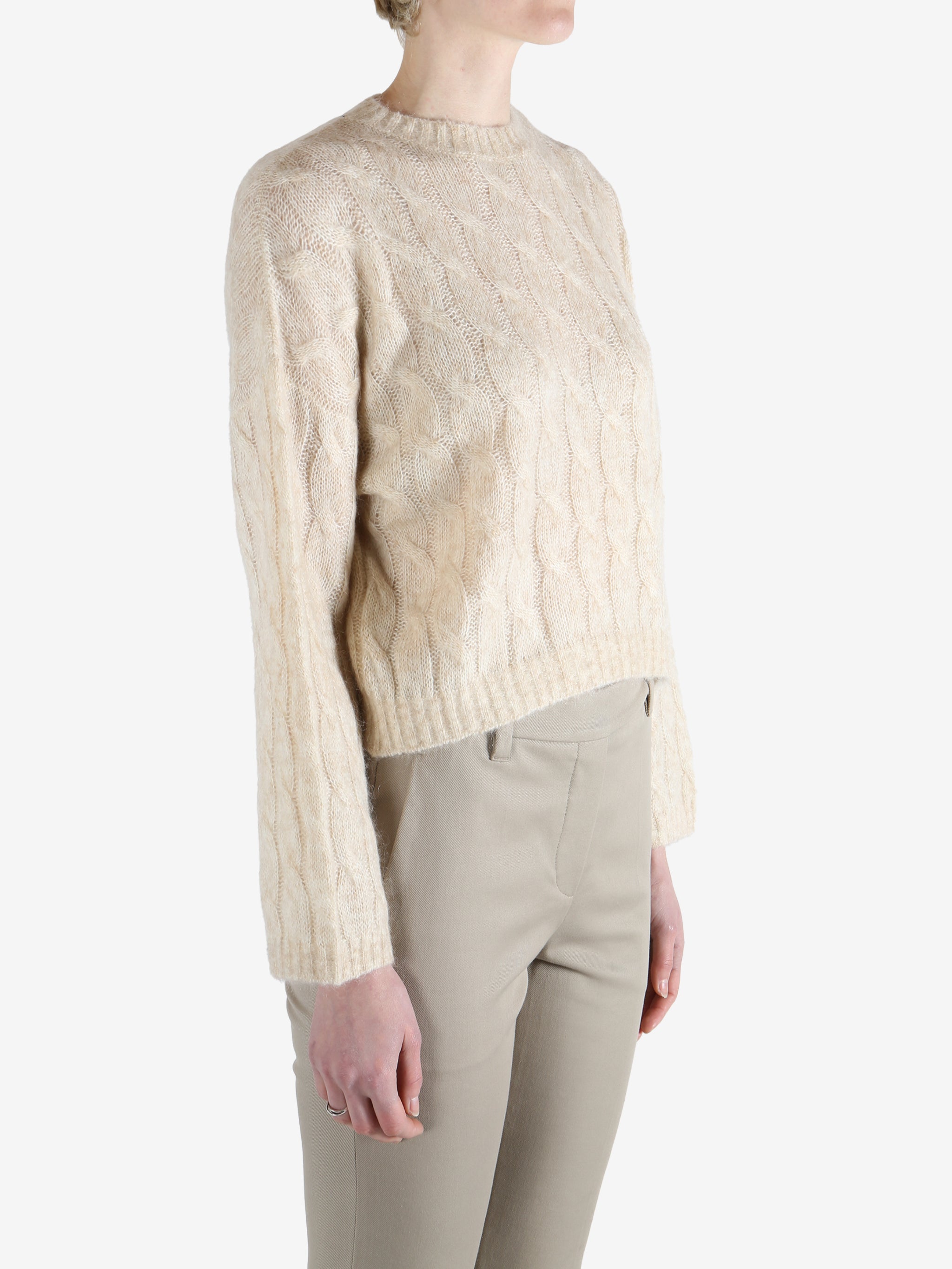 beige cable knit sweater worn by a person, showing the sweater fit