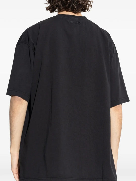 Black t-shirts worn by a person, showing the t-shirts fit