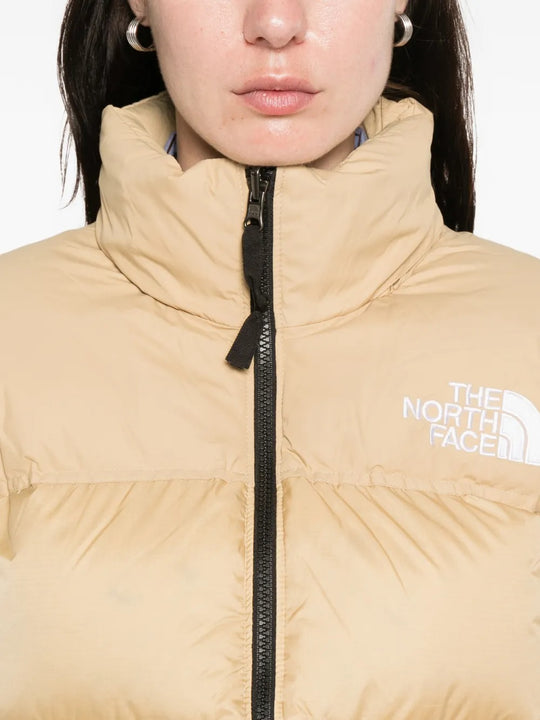Close up of tan jackets, showing texture of the nylon and recycled down and recycled feather fabric