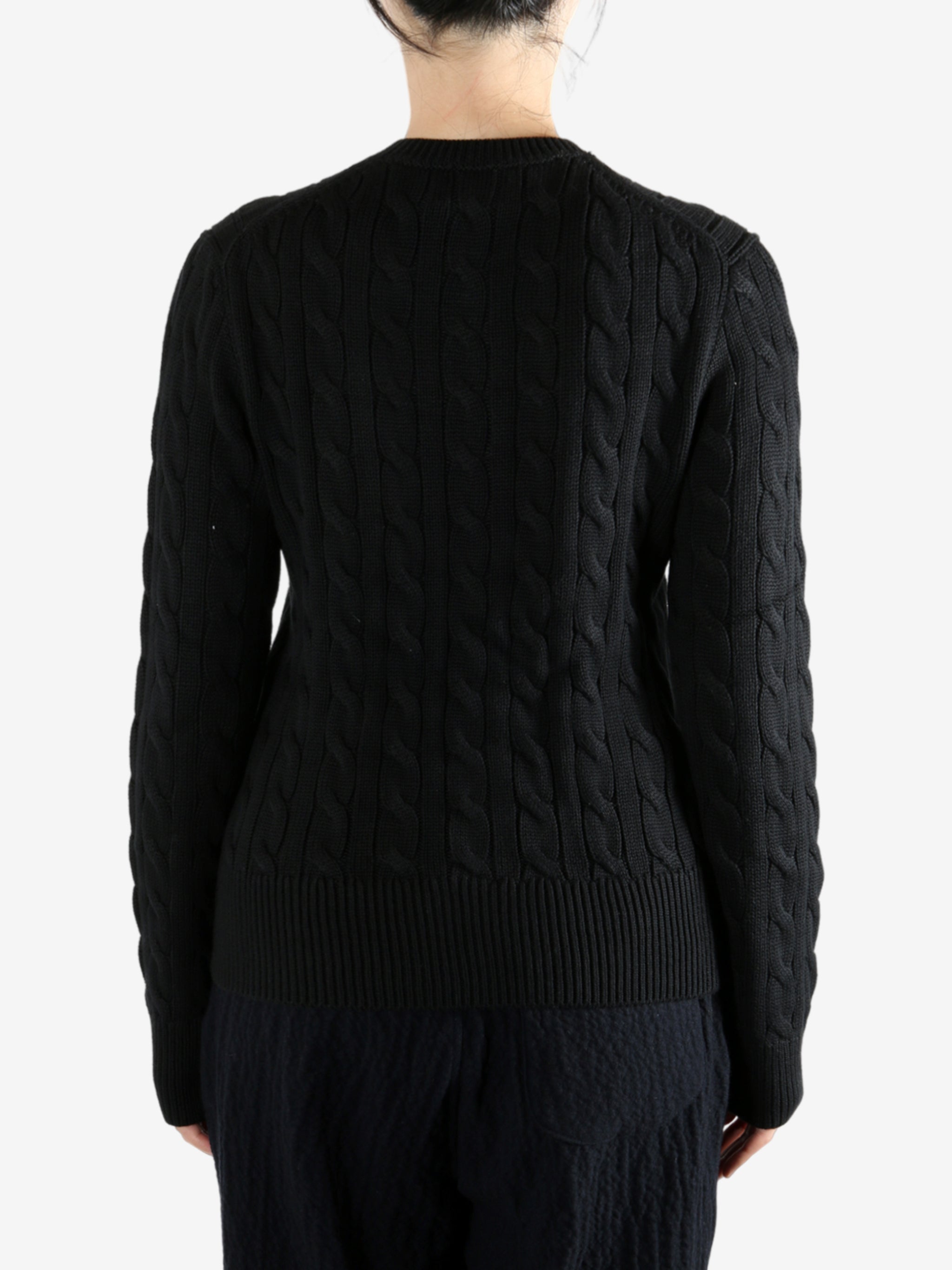 Black knitwear worn by a person, showing the knitwear fit