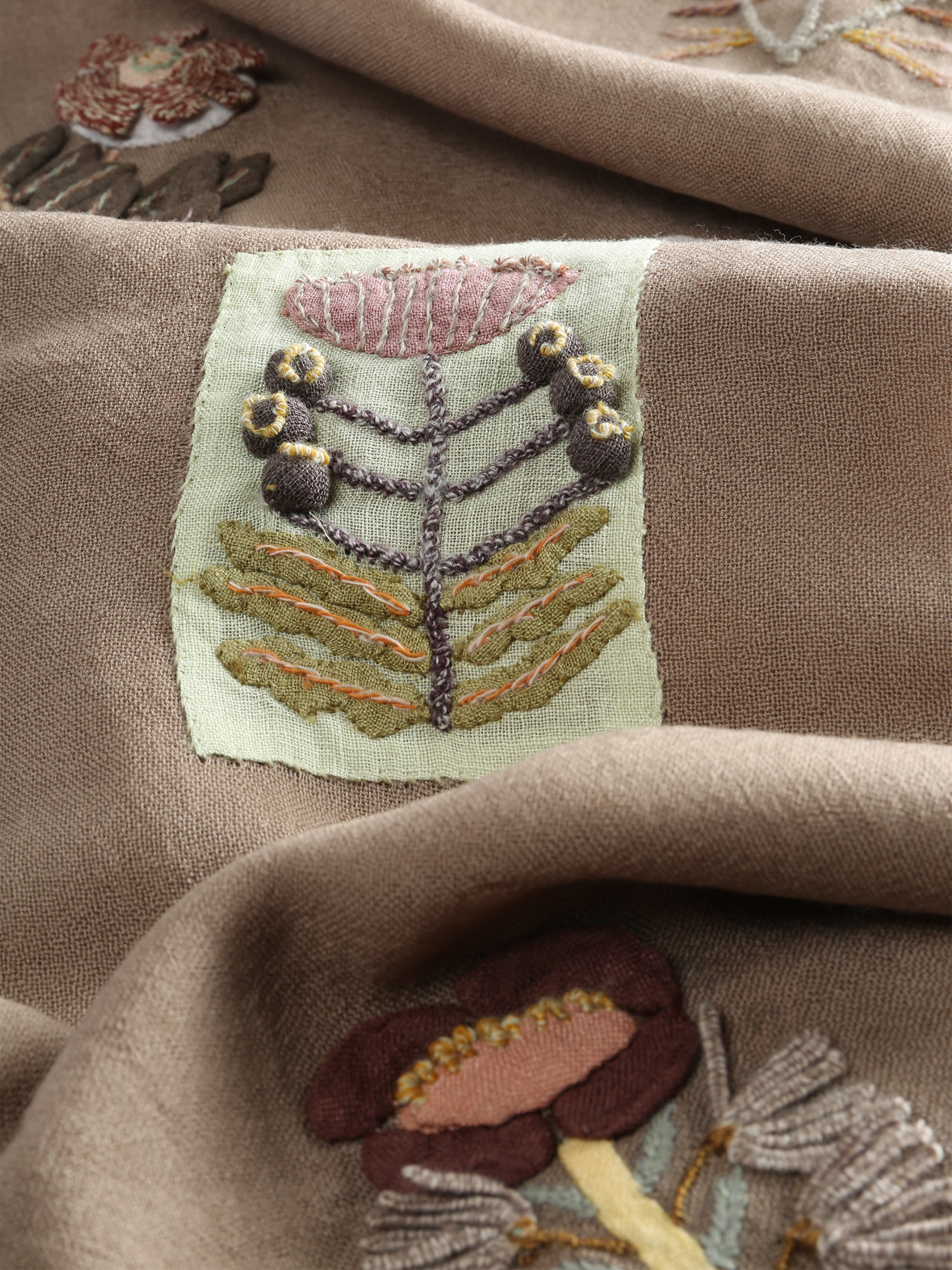 Close up of tan scarves, showing texture of the wool and linen fabric