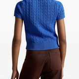 Blue knitted polo shirt worn by a person, showing the shirt's fit