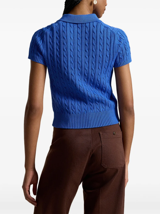Blue knitted polo shirt worn by a person, showing the shirt's fit