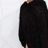 Black knitwear worn by a person, showing the knitwear fit