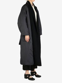Black coat worn by a person, showing the coat fit
