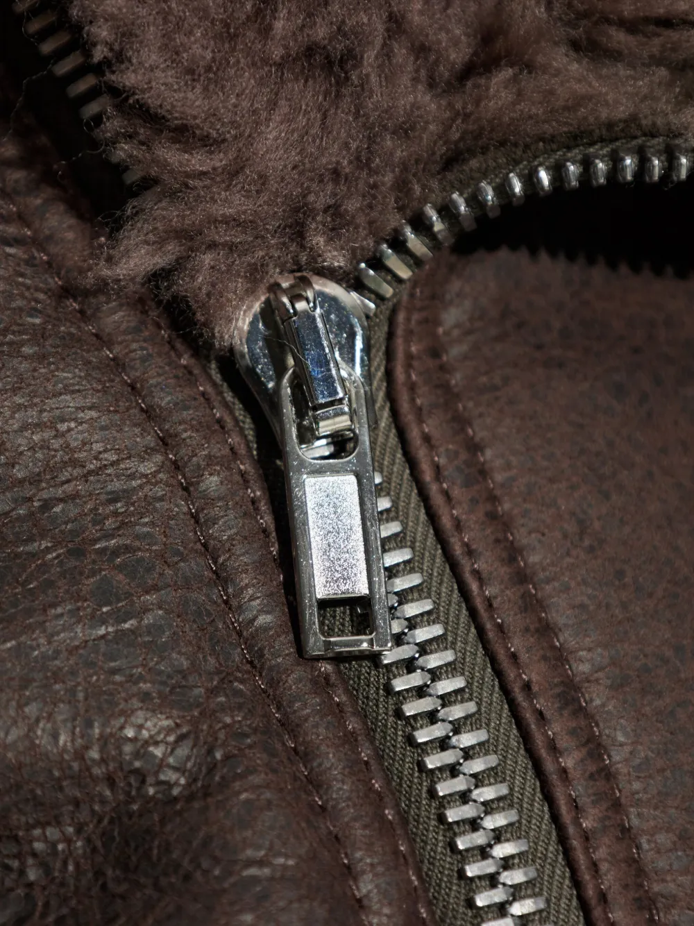 Close up of the brown jacket, showing texture of the leather and wool fabric