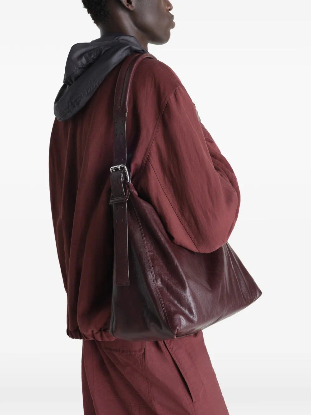 Brown leather handbag worn by a person, showing the bag fit