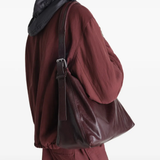 Brown leather handbag worn by a person, showing the bag fit