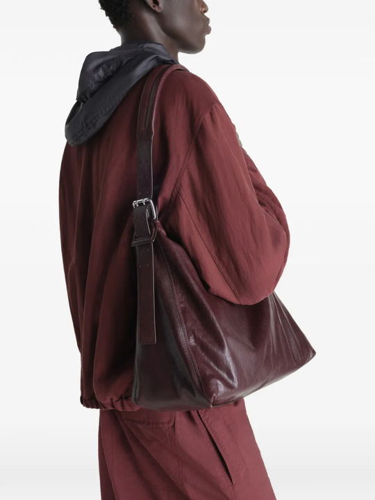 Brown leather handbag worn by a person, showing the bag fit